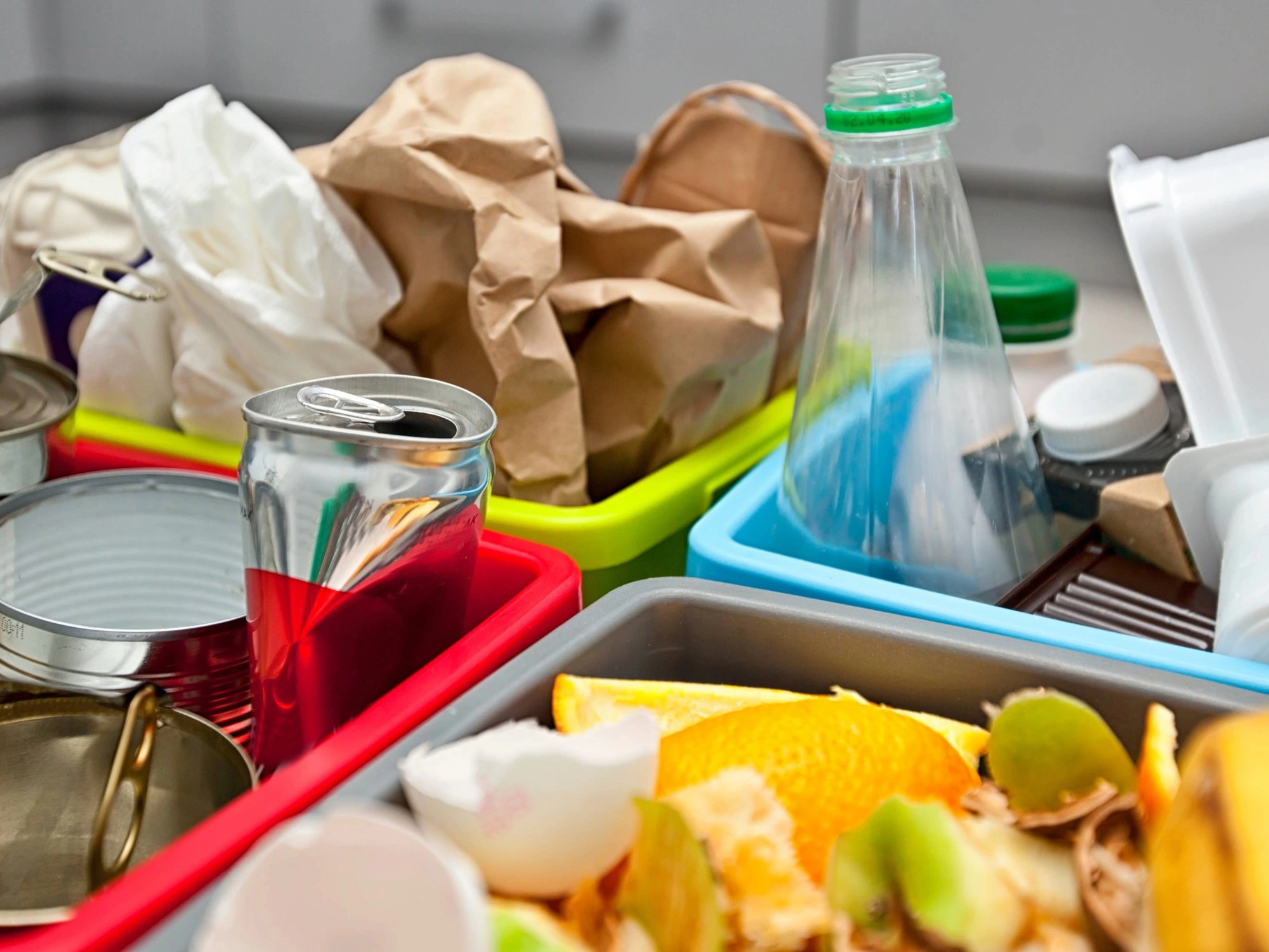 Waste being sorted for recycling, showing separate containers for different materials like food waste, plastic, metal, and paper.